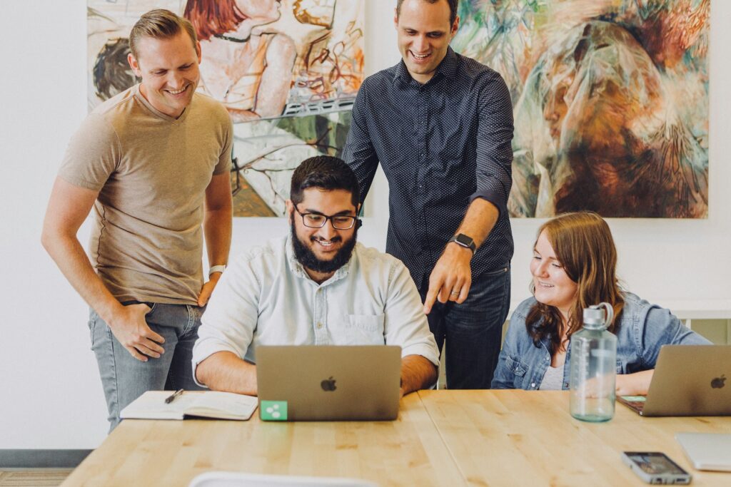 Equipe reunida ao redor de um notebook, sorrindo